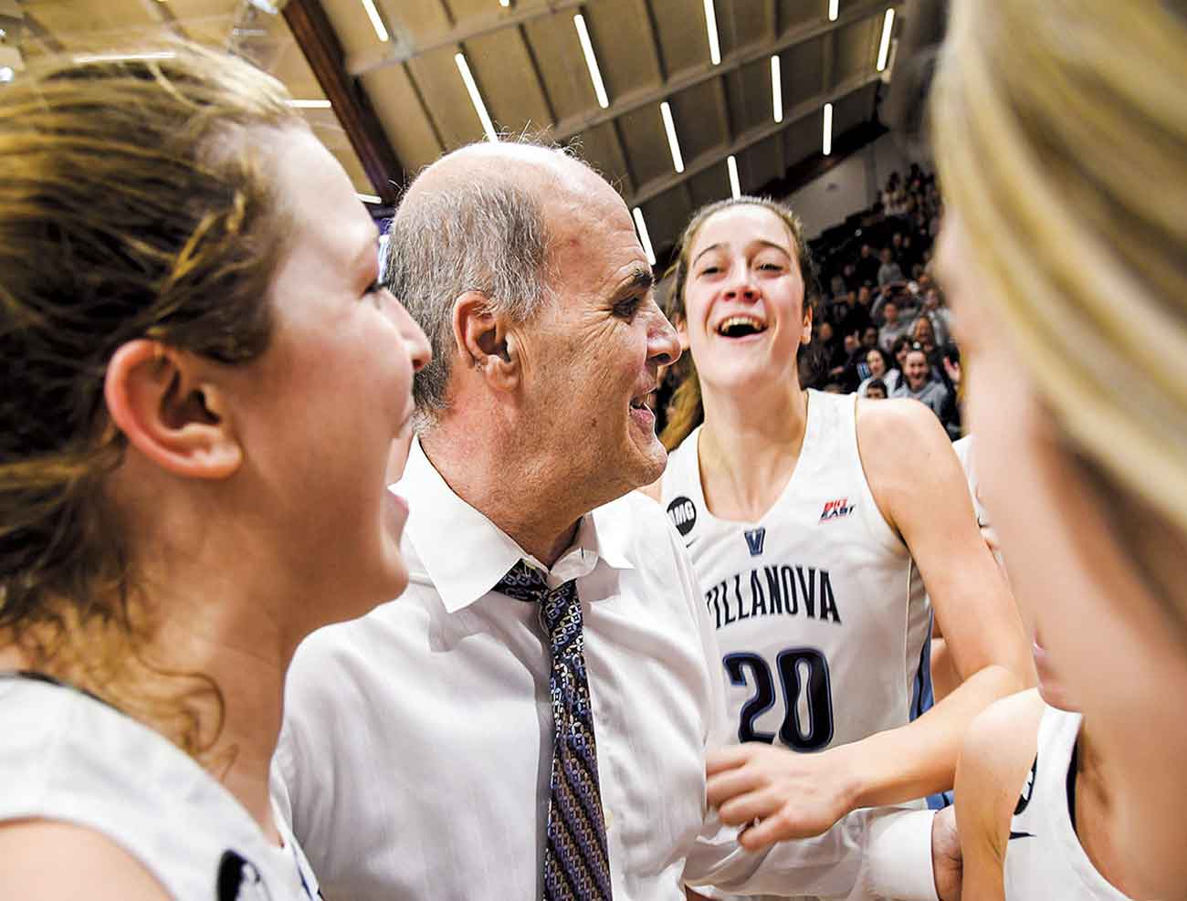 Harry Perretta talking with women’s basketball players on the sidelines during a game