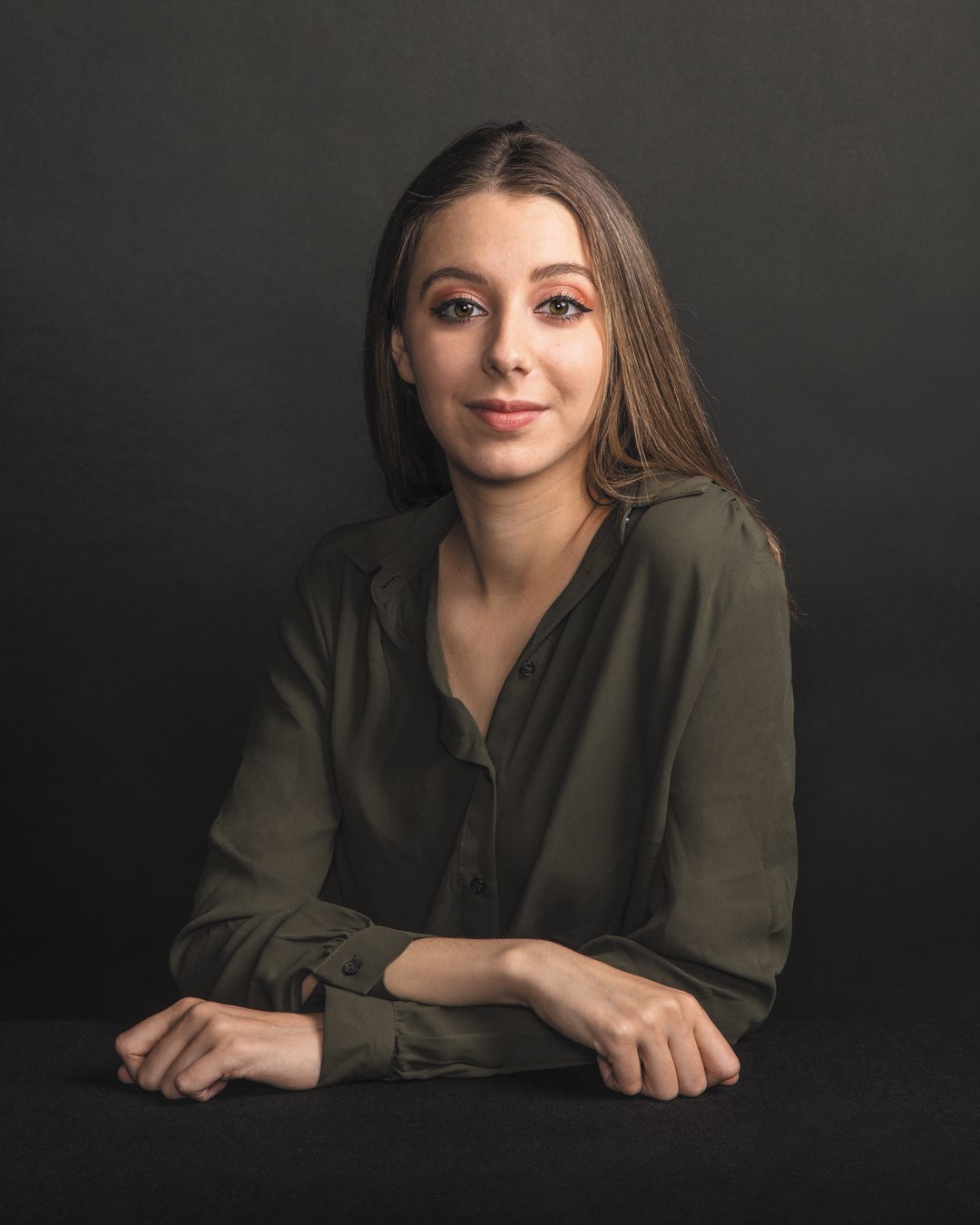 Rising sophomore Julia Jureidini leaning with arms crossed in an olive-colored dress blouse