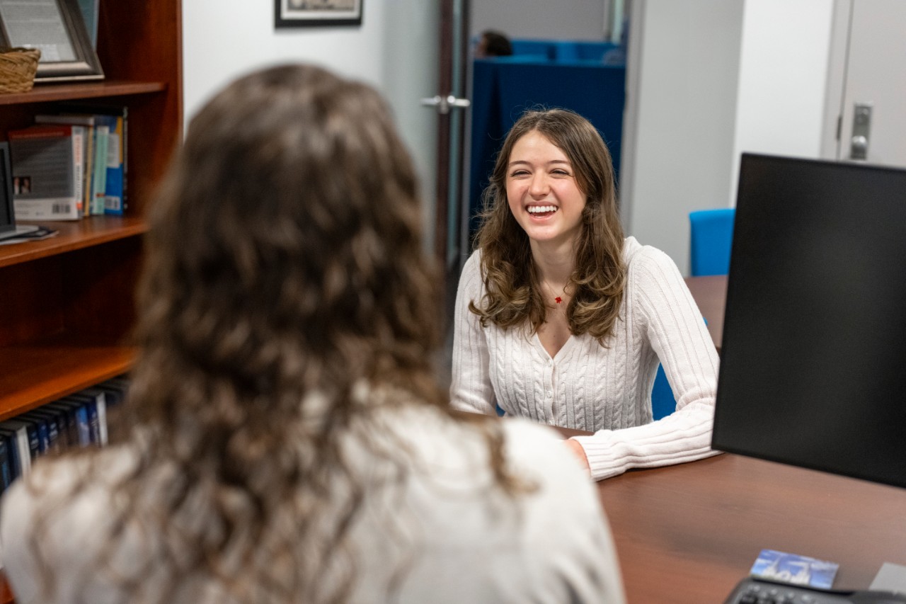 CSO692_20250415_1376 Student speaking to a staff member in an office in the Career Center.