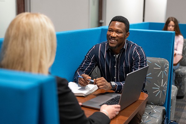 coaching-financial-page staff member working with student, seated at a table