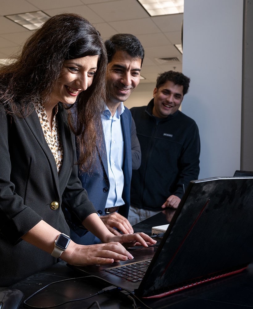 Three graduate engineering students look at a computer.