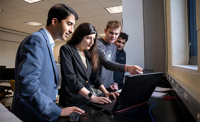 Department of Electrical and Computer Engineering Associate Professor Mojtaba Vaezi works with students at a computer.
