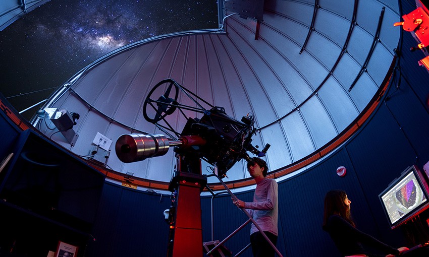 Student observes the night sky through a telescope. Student observes the night sky through a telescope.
