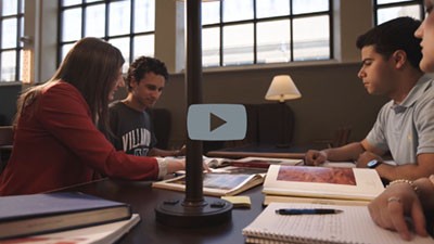 Whitney Martinko, PhD, sitting with three students at a table in the library. Whitney Martinko, PhD, sitting with three students at a table in the library.