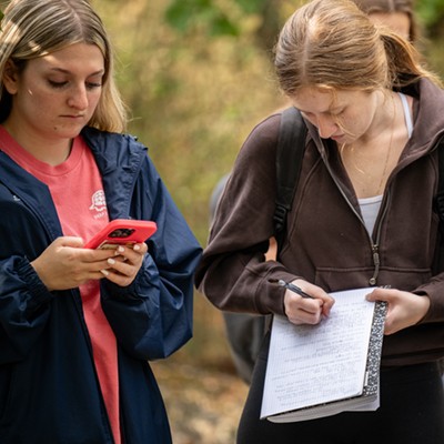 Students taking notes on their phone (left) and notebook (right).