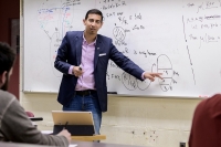 Mathematics professor in front of whiteboard with equation