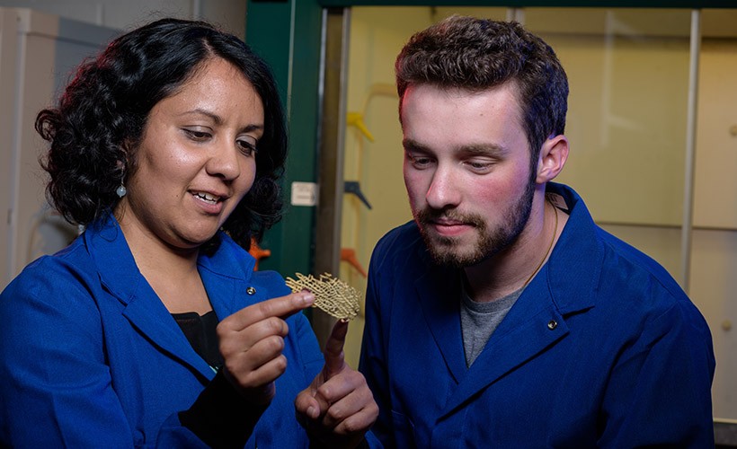 A student and professor study a piece of coral. A student and professor study a piece of coral.