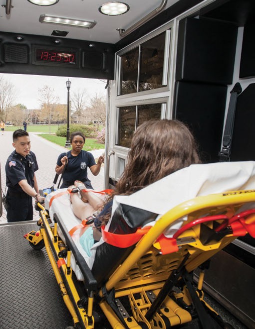 Two emergency response workers helping someone in an ambulance