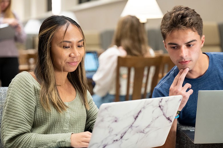 Male and female student viewing laptop
