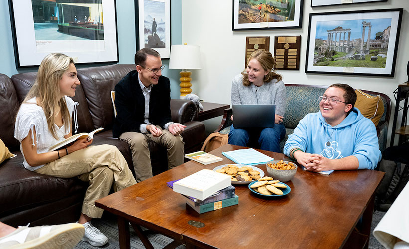 Students and professor sitting on couches discussing book