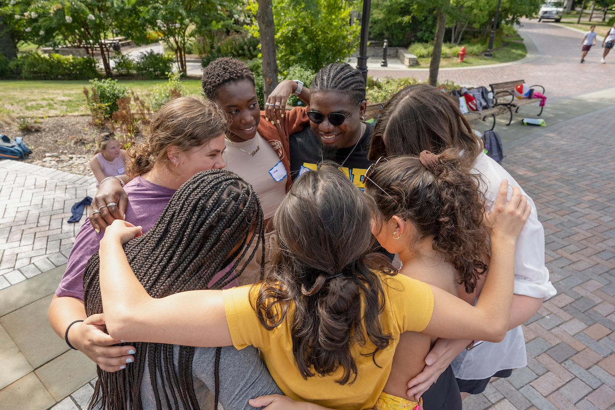 Students wrapped in a huddle smiling at each other.